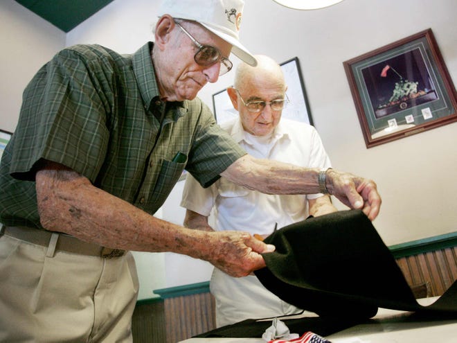 World War II Marine Corps veterans and survivors of Iwo Jima, Bob Gasche, right, and Clif Cormier prepare to drape a black scarf over a Fourth Marine Division plaque honoring fellow Iwo Jima survivor Clair Chaffin.