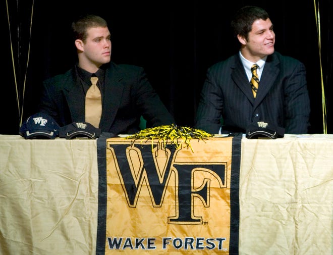 Photo by DARON DEAN/St. Augustine RecordNease defensive linemen Frank Souza (left) and John Gallagher sign with Wake Forest iin February in the school's auditorium.