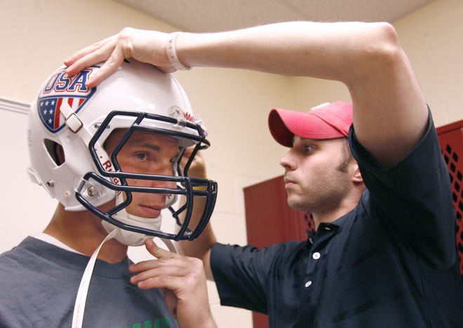 Jordan Lynch gets fitted for his USA Football helmet Saturday by Anthony Colangelo of Riddel. Lynch and the rest of Team USA begin practice today at Walsh University for the International Federation of American Football Junior World Championship.