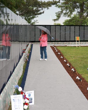Patricia Santos, of Plymouth, reads the names as she walks along the Vietnam Memorial Moving Wall.