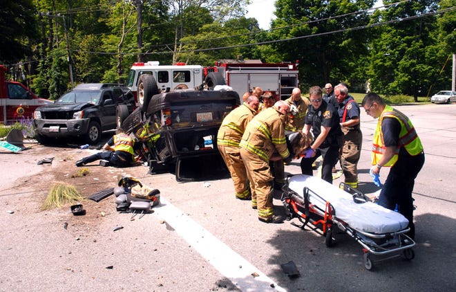 Rescue personnel lower a victim of this morning's rollover accident onto a stretcher. The accident occured at the intersection of Clay Pond and County roads in Bourne.