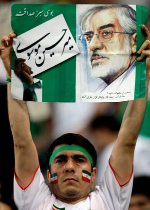 Iranian soccer fan holds a poster with the image of Iranian opposition leader Mir Hossein Mousavi during the 2010 FIFA World Cup Asia group 2 qualifying soccer match against South Korea at Seoul World Cup Stadium in Seoul, South Korea, Wednesday, June, 17, 2009. Mousavi supporters have been protesting the disputed June 12 presidential election results and violence against his followers. Five Iranian soccer players, including captain Ali Karimi, wore green wristbands - the signature color of his movement - in an apparent sign of support for Mousavi at the game.