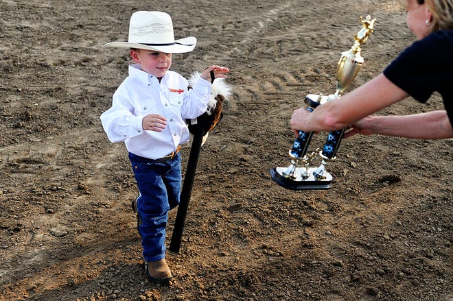 Tyler Gini, 3, of Hallsville picks up his trophy for being named Best Dressed Cowboy Thursday night during Hallsville Heritage Days.