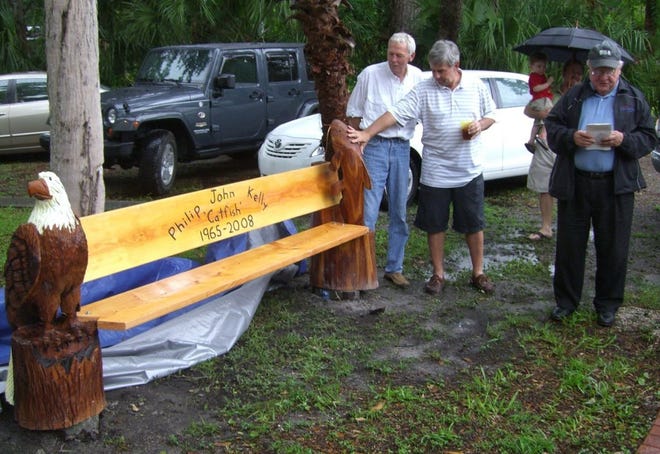 JACKIE ROONEY/For ShorelinesMike Holtsinger (from left) and Bobby Duval watch June 7 as the Rev. Robert Hanlon blesses the Phil "Catfish" Kelly bench, in front of the Palm Valley Community Center. Kelly, who chaired the Lighted Boat Parade Palm Valley, died last year.