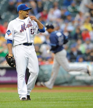 Mets pitcher Johan Santana wipes his face as Tampa Bay’s Carlos Pena rounds the bases behind him in the seventh inning.