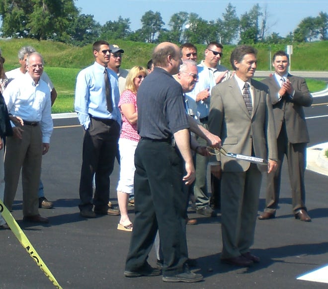 Jonesville Local Downtown Finance Authority Chairman Rick Schaerer, Village President David Steel and Michigan Department of Transportation Economic Development Specialist Michael Leon stand back from the construction tape ribbon cutting to celebrate the completion of the Gaige and Reading street project in Jonesville Wednesday, June 24, 2009. Area residents, Martinrea employees, state representatives, MDOT employees and village officials watched the ceremony and then walked to the M-99 roadside park for refreshments.