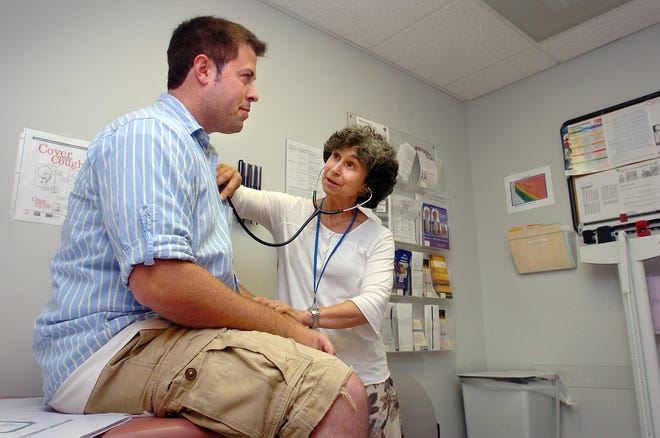 Dr. Martha Karchere, right, checks heart rate of patient Mark Wilson at Manet Community Health Center in North Quincy.