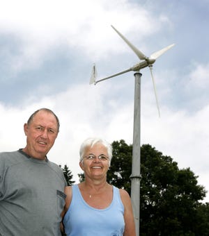 Frank Towns and his wife, Pam, stand in front of the wind turbine they installed Saturday at their Pilot Knob Avenue NE home. It took the Towns nearly two years to get the permits he needed to install the wind turbine on his property, but it only took 10 minutes to build it.