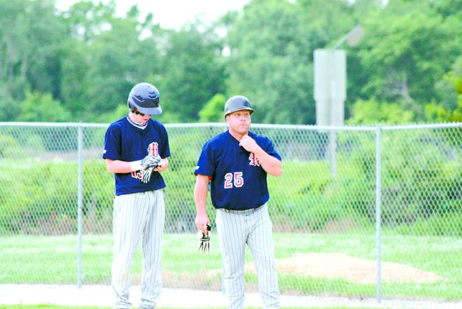 Tanner Schreck and assistant coach Rick Chick discuss strategy in Post 136's game with East Moline last week.
