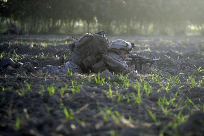 A U.S. Marine from the 2nd Marine Expeditionary Brigade, 1st Battalion 5th Marines takes cover in a farm fields after landing by helicopter in an overnight night air assault near the Taliban stronghold of Nawa in Afghanistan's Helmand province Thursday. Thousands of U.S. Marines poured from helicopters and armored vehicles into Taliban-controlled villages of southern Afghanistan Thursday in the first major operation under President Obama's strategy to stabilize the country.