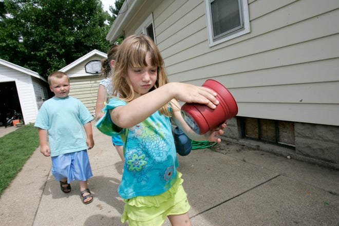 Maddie Meyer (right), 7, inspects a plant potter as her friend Philip Williams, 4, both of Rockford walks behind her Friday, July 3, 2009, along the 1900 block of North Bruner Street in Rockford. The friends planted tomato and sunflower seeds.