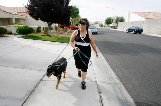 In this photo taken on June 13, 2009, Leslie Fuller, 51, walks her dog Sirabi near her in Las Vegas. Fuller says she has gained back weight she lost due to stress eating. (AP Photo/Isaac Brekken)