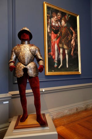 This June 22, 2009 photo shows "Child's Armor of Philip III", left, also seen in the painting at right, "Allegory of the Education of Philip III," by Justus Tiel, which are part of the exhibit, "The Art of Power: Royal Armor and Portraits from Imperial Spain," seen at the National Gallery of Art in Washington. (AP Photo/Jacquelyn Martin)