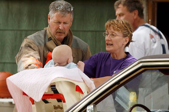 Shawnee County firefighter Dennis Whitegon, left, and Laura Lord tend to a baby at 215 W. Railroad in Willard. Lord was taking care of the baby after its mother was injured in a stove fire. Lord is a neighbor of the injured woman.
