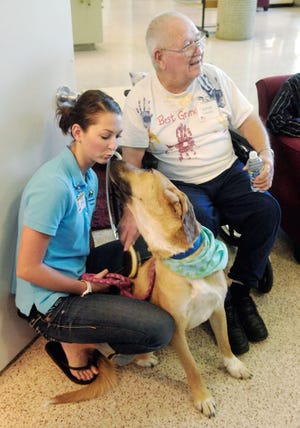Paige Rakes, left, a student at the MU School of Health Professions, introduces Vince Twenter, a client in the university’s Eldercare program, to a dog brought for a visit from Columbia Second Chance.