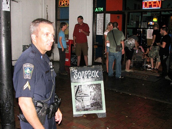 Cpl. Doug MacNeish stands in front of The Soapbox about 12:45 a.m. early Saturday morning. He was among the officers responding to a call about a fight between a man and a woman. In a separate incident at the same time, a man was passed out in the lobby, and emergency medical technicians were called to assist him.