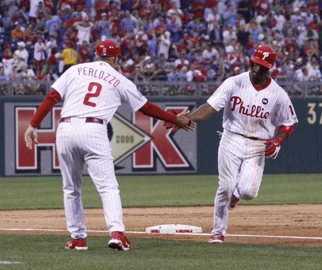 Philadelphia Phillies shortstop Jimmy Rollins celebrates with third base coach Sam Perlozzo after he hit a solo home run against the Chicago Cubs in the third inning Tuesday, July 21, 2009, in Philadelphia.