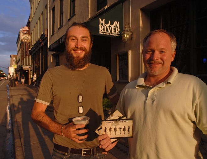 Iraq War veterans Jason Hurd left, and Scott Meeker promote the upcoming Combat Paper Project by distributing information at downtown bars, including Moon River Brewing Company which is hosting a reception for the event. (John Carrington/Savannah Morning News)