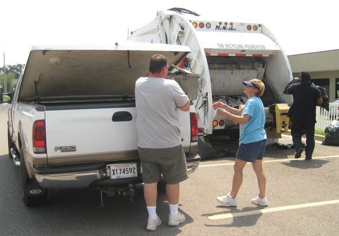 Recycling Road Show workers (right) help an Ascension Parish resident unload recyclables from the back of his truck during the July 11 Recycling Road Show at the Prairieville Wal-Mart. The Road Show collected 3.5 tons of recyclables from 120 vehicles.