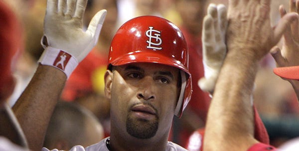 St. Louis Cardinals' Albert Pujols is congratulated by teammates in the dugout after hitting his second home run of the night against the Arizona Diamondbacks during the sixth inning of a baseball game Friday, July 17, 2009, in St. Louis. Pujols hit his first home of the game during the fourth inning. (AP Photo/Jeff Roberson)