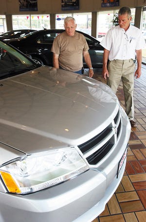 Rod Dennis, left, and Lakis Ford Dodge salesman John Sholl look over a 2009 Dodge Avenger Dennis, of Knoxville, bought Monday afternoon. Dennis traded a 1996 Ford F150 pickup truck for the Dodge and will receive $4,500 in the Car Allowance Rebate System.