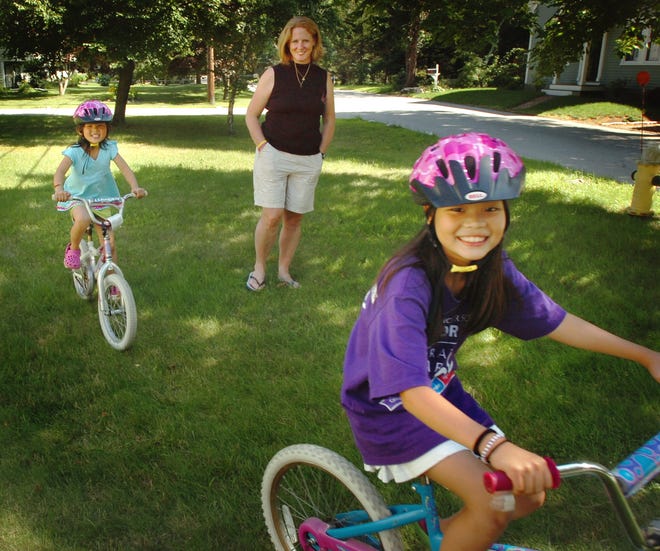 Wednesday, July 15, 2009 Cohasset resident Laura Vigneau, a single mother adopted daughters Lydia, 8 and Lieren, 7 from China when they were very young. Lydia battled Lukemia. Five years later, she is healthy. Laren , 7, left, her mom Laura, and Lydia ,8, right ride their bicycles in their front yard.
