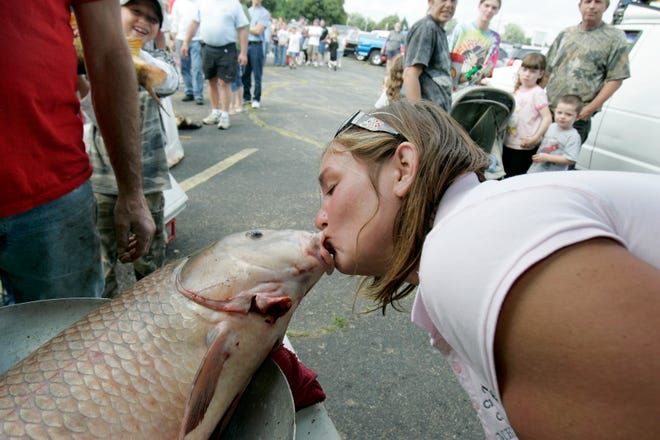 Sarah Wescott, member of Coon Creek Casters Fishing Club, kisses a 24.94 pound carp caught by Jimmie Keen of Roscoe during the 21st annual Carp-A-Thon on Aug. 1, 2009, at the United Auto Workers Local 1268 Hall on Chrysler Drive in Belvidere. The event is sponsored by Coon Creek Casters Fishing Club. Keen won the fishing tournament.