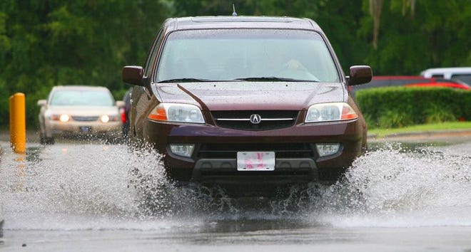 A motorist drives through water after a heavy rain shower in the Lowe's shopping center on Southwest College Road in Ocala on Friday.
