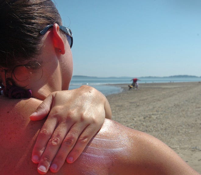 Ashly Lasko, 24, of Braintree, applies SPF 15 sunscreen to her skin at Wollaston Beach.