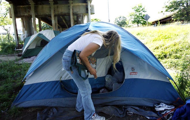Judy McGill closes her tent in an area where a camp has sprung up under a highway in Providence.