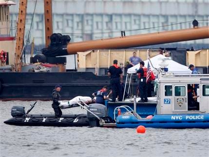 Emergency personnel move what appears to be a body from the Hudson River as seen from Hoboken, NJ, Sunday, Aug. 9, 2009. Police boats and divers on Sunday circled the wreckage of a submerged tourist helicopter as investigators resumed their search for debris and missing bodies from the helicopter and a small plane that collided in midair, raining wreckage down on the New Jersey waterfront and into the Hudson River.