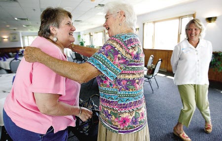 Judy Beaudoin, left, of Portsmouth and Kitty Geilen of Eliot, Maine, middle, hug as Lynn Del Chaquette of Portsmouth, far right, watches during the Pier II restaurant reunion held Sunday at the Elks Lodge in Portsmouth.
