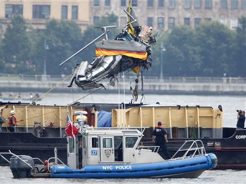 The wreckage of a helicopter is lifted by crane from the Hudson River and placed on a boat as seen from Hoboken, N.J., Sunday, Aug. 9, 2009. Divers recovered a piece of a submerged helicopter and a fifth body Sunday as investigators searched the Hudson River for wreckage from the helicopter and a small plane that collided in midair, killing nine people.