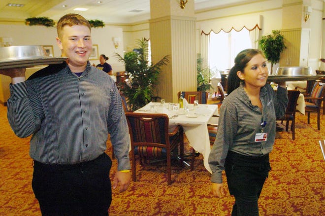 Kevin Roseberg of Hingham and Stephanie Lawson of Hanover, who work at Linden Ponds in Hingham and received $4,000 scholarships provided by the residents of Linden Ponds, carry trays across the Oakleaf Clubhouse’s dining room Wednesday.