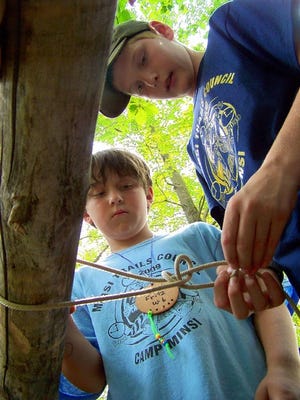 Boy Scout Kyle McCarthy demonstrates how to tie a taut line hitch as Webelo scout Robert Fritz observes.