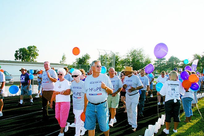 Individuals who beat cancer walk around the track carrying balloons on the survivor lap at the 2009 Relay for Life at Sunnylane Field.