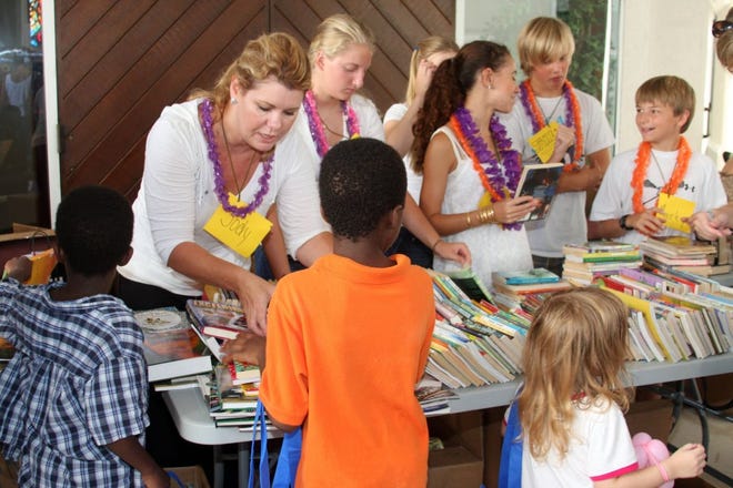 MAGGIE FITZROY/StaffTeen and parent volunteers from Ponte Vedra Beach give children free books. About 1,000 children, parents and grandparents attended this year's Back to School with BEAM event.