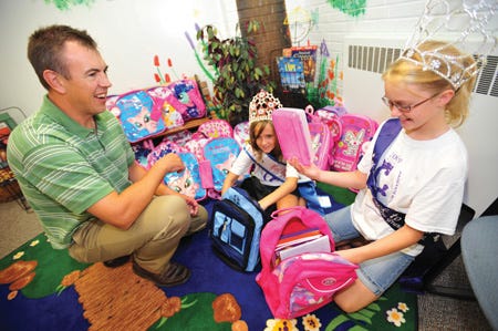 Josh Bradshaw / Times staff
C.B. Smith School Principal A.J. Schroff receives backpacks and school supplies from Camiryn Irving, 11, and Kadryn Hemmer, 10, both of Pekin. Money to purchase supplies was raised through the Compassionate Crowns pageant program.