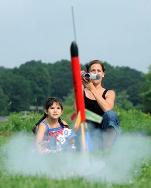 Students in the Champions Science Adventures summer camp's Space & Rocketry program at Westborough High School launch their mini rockets. Samantha Feldman, 6, watches her rocket take off as her mother, Audrey, videotapes the event.