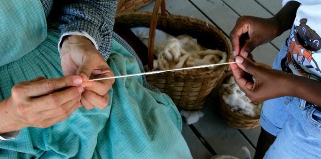 In this July 28, 2009 photo, Lesley Royce, left, a volunteer at the Camp Milton Civil War camp, helps a camper make thread from wool during a demonstration of life during the 1800s, in Jacksonville, Fla. The camp was host to children from the Jacksonville summer camp program.(AP Photo/Phil Coale)