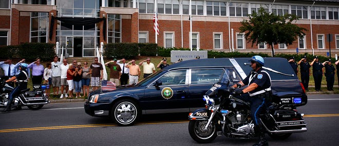 The widow of Weymouth police officer Michael Davey and his parents stood with the members of the Weymouth Police Dept outside the station as a hearse with patrolman Davey's body passed. He was killed while working at a construction site Monday.