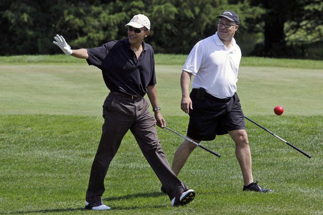 President Barack Obama waves Monday as he walks with Dr. Eric Whitaker as they play golf during his vacation on Martha’s Vineyard in Oak Bluffs.