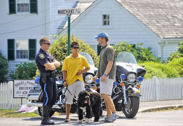 A Barnstable police officer talks with the dog handlers for the Kennedy family as they take Sen. Edward M. Kennedy's furry friend Cappy, a Portuguese water dog, for a walk yesterday.