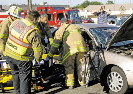 A young man holds his head while he watches the Portsmouth Fire Department use the Jaws of Life to extricate a person from vehicle. The car was involved in a two-vehicle crash on Woodbury Avenue on Thursday.