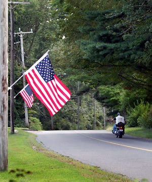 A motorcyclist passes by a display of patriotism on Main Street in Plympton.