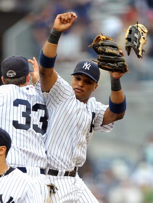 New York's Nick Swisher, left, loses his glove as he leaps to bump bodies with teammate Robinson Cano on Saturday as they celebrate their 10-0 win over the Chicago White Sox.