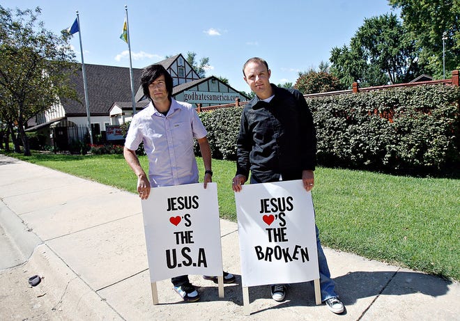 Craig Gross and Jason Harper, co-authors of the book “Jesus Loves You This I Know,” stand outside the Westboro Baptist Church, 3701 S.W. 12th, with picket signs delivering a message opposite the signs church members usually carry. Gross and Harper are traveling the United States promoting the book’s message.