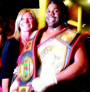 Luke Burton, formerly of Monmouth, holding two of his MMA championship belts. Next to Luke is his wife Amy.
