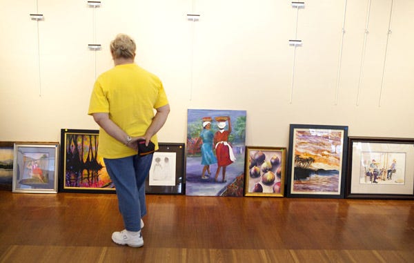 Elaine Frameli looks over works waiting to be hung for the exhibit “Season of Mists” at the Brick City Center for the Arts in Ocala on Tuesday. The exhibit runs through Sept. 30.