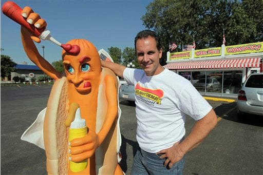In this photo taken Wednesday, Sept. 2, 2009, Johnny Cappas, co-owner of Johnny's WeeNee Wagon, poses with his Lucky Dog, a gift from his girlfriend, in Markham, Ill. Cappas, a one-time "drug kingpin" as the papers called him, was making $25,000 a week selling cocaine before he went to federal prison in 1989 for what turned out to be a 15-year term. He was released from prison in 2004 and this summer with a partner bought the hot dog stand.